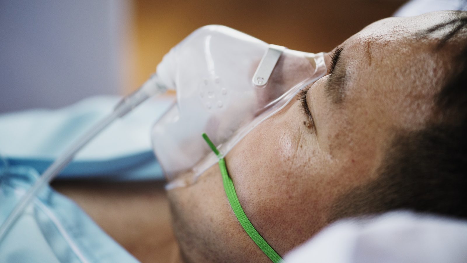 A sick man in a hospital receiving oxygen